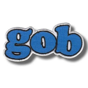 Op de afbeelding: Een blauw geborduurd embleem met het woord "gob" in een afgeronde lettertype. De blauwe letters hebben een witte omtrek en een zwarte rand, op een witte achtergrond.