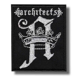 Può includere: Toppa ricamata nera con la scritta "architects" sopra una lettera "A" bianca stilizzata con un design a corona. La toppa è rettangolare e ha un bordo nero.