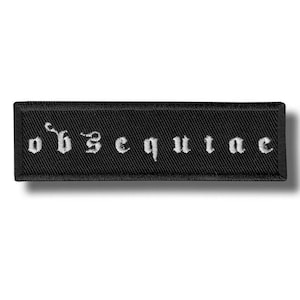Pode incluir: Patch retangular preto com a palavra "obsequiae" bordada em letras góticas brancas. O patch tem uma borda preta e uma superfície texturizada.