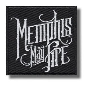 Könnte beinhalten: Quadratischer schwarzer Aufnäher mit weiß gesticktem Text „Memphis May Fire“ in einer stilisierten gotischen Schrift. Der Aufnäher hat einen schwarzen Rand und ist wahrscheinlich ein Accessoire für Kleidung oder Taschen.
