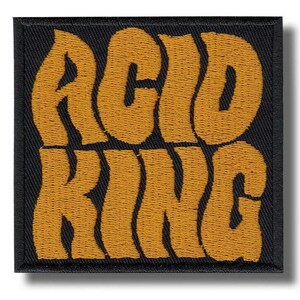 Peut inclure: Écusson brodé avec les mots "ACID KING" en police orange audacieuse et ondulée. Le texte est cousu sur un fond carré noir. L'écusson a un bord net et fini.