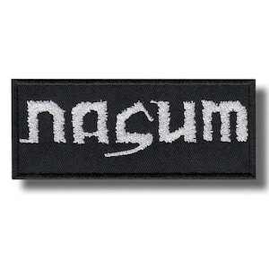 以下が含まれることがあります： 白のスタイリッシュな大文字で「nascum」という言葉が刺繍された長方形の黒いパッチ。 パッチには黒い縁取りがあり、衣類やアクセサリーに縫い付けるように設計されています。