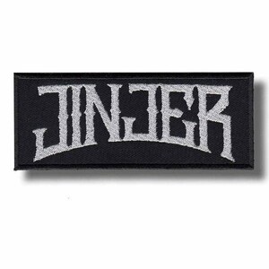 May include: Black rectangular patch with the word "JINJER" embroidered in white, stylized, gothic lettering. The patch has a black border and is likely designed to be sewn onto clothing or accessories.