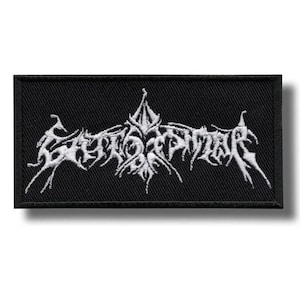 May include: Black rectangular patch with white embroidered text. The text is stylized and appears to be a band logo. The patch has a black border and is likely made of fabric. The design is intricate and detailed.
