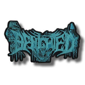 Op de afbeelding: Geborduurde patch met het woord "BEHEMOTH" in turquoise, gotische letters. De patch heeft een zwarte rand en een gedetailleerd ontwerp, inclusief een schedelachtig beeld in de letters. Voor kleding of accessoires.
