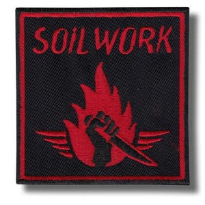 May include: Black square patch with a red border. The patch features the word "SOILWORK" in red block letters at the top. Below the text is a red flame design with a black fist holding a knife. The patch has a white background.