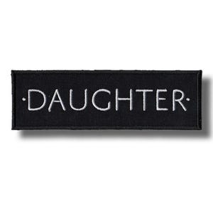 以下が含まれることがあります： 黒い長方形のパッチ。中央に白い文字で「DAUGHTER」と刺繍されています。パッチは黒い縁取りがあり、衣類やアクセサリーに縫い付けたり、アイロンで接着したりするように設計されています。