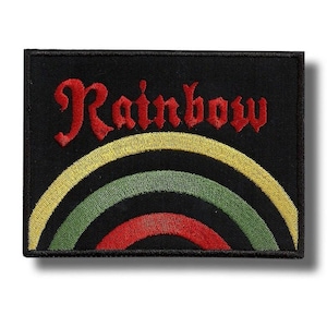 Op de afbeelding: Zwart rechthoekig embleem met het woord "Rainbow" in rood script boven een geel, groen en rood regenboogontwerp. De patch is waarschijnlijk voor kleding of accessoires.