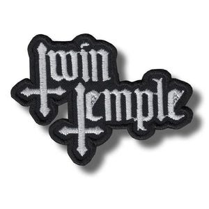 Puede incluir: Parche bordado negro con las palabras "Twin Temple" en letras góticas blancas. El parche tiene un diseño de cruz a cada lado. El parche está sobre un fondo blanco.