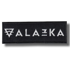May include: Black rectangular patch with the word "ALAZKA" embroidered in white. The patch features a stylized design before the "A" and after the "Z". The patch is likely for clothing or accessories.