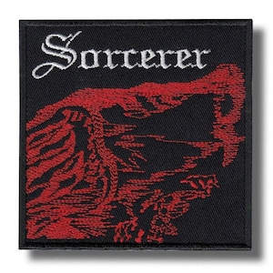 Op de afbeelding: Vierkante zwarte patch met het woord "Sorcerer" in wit script boven een rode illustratie. Het rode ontwerp is een landschap of een abstracte figuur. De patch heeft een zwarte rand.