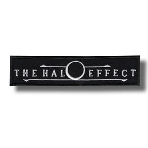 Puede incluir: Parche rectangular negro con texto bordado blanco que dice "THE HALO EFFECT". El diseño incluye un círculo blanco en el centro del texto. El parche es probablemente para ropa o accesorios.