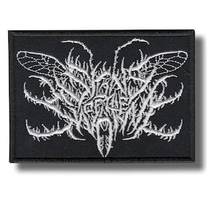 May include: A black rectangular patch with a white embroidered design. The design features an abstract pattern with wing-like shapes and intricate details. The patch has a black border and a shadow.