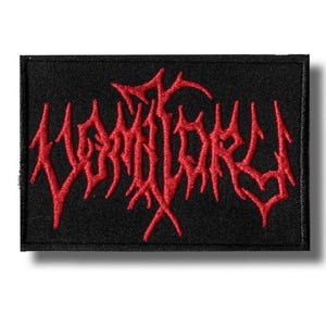 Op de afbeelding: Zwart rechthoekig embleem met het woord "MORTUARY" geborduurd in rode, gotische letters. De patch heeft een zwarte rand en is waarschijnlijk ontworpen om op kleding of accessoires te worden genaaid of gestreken.