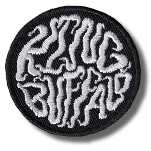 Op de afbeelding: Een ronde, zwart geborduurde patch met de woorden "ESSAYS BRAIN" in witte, gestileerde letters. De patch heeft een zwarte rand en een getextureerde uitstraling, geschikt voor kleding of accessoires.