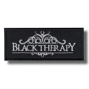 May include: Black rectangular patch with white embroidered text and decorative flourishes. The text reads "BLACK THERAPY" in a stylized font. The patch is likely for clothing or accessories.