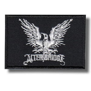 Op de afbeelding: Zwart geborduurde rechthoekige patch met een witte adelaar met uitgespreide vleugels. De tekst "ALTER BRIDGE" is eronder in het wit geborduurd. De patch heeft een zwarte rand.