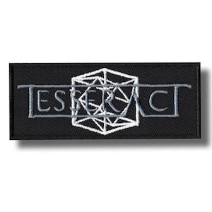 Könnte beinhalten: Schwarzer rechteckiger Aufnäher mit dem Wort "ESPERACT" in Grau und Weiß gestickt. Das Design beinhaltet eine geometrische Form in der Mitte. Der Aufnäher ist wahrscheinlich für Kleidung oder Accessoires.