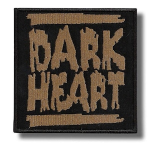 Pode incluir: Patch quadrado preto com as palavras "BARK HEART" bordadas em uma fonte desgastada de cor marrom. O design é simples e arrojado, com o texto centralizado no quadrado.