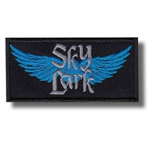 Puede incluir: Un parche rectangular negro con la inscripción "Sky Lark" en una fuente estilizada, con alas azules. Las alas están bordadas con un diseño detallado de plumas. El parche es para ropa o accesorios.
