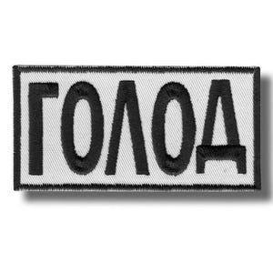 Puede incluir: Un parche rectangular con la palabra "ГОЛОД" bordada en negro sobre un fondo blanco. El parche tiene un borde negro y un efecto de sombra, lo que le da una apariencia tridimensional.