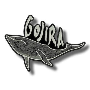 Könnte beinhalten: Gestickter Aufnäher mit einem Wal-Design und wirbelnden Mustern. Das Wort "GOJIRA" ist in einer stilisierten Schriftart über dem Wal angeordnet. Der Aufnäher hat einen schwarzen Rand und einen weißen Hintergrund.