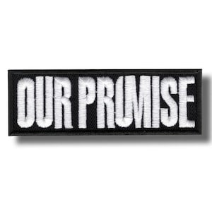 May include: Black rectangular patch with the embroidered text "OUR PROMISE" in white. The patch has a black border and a shadow effect, giving it a three-dimensional appearance. The text is in a bold, sans-serif font.
