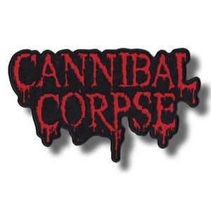 Puede incluir: Un parche negro con las palabras "CANNIBAL CORPSE" en letras rojas goteantes. El parche tiene una forma irregular y el texto parece bordado.