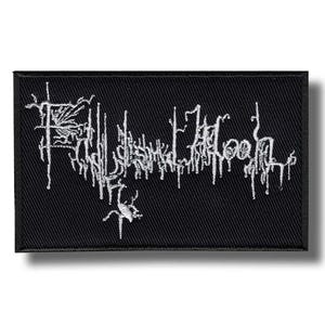 May include: Black rectangular patch with white embroidered text. The text appears to be a band name or logo in a stylized, gothic font. The patch has a woven texture and a shadow effect.