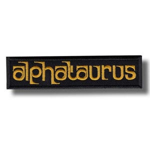 May include: Black rectangular patch with the word "alphataurus" embroidered in gold thread. The patch has a black border and a shadow effect, giving it a three-dimensional appearance.