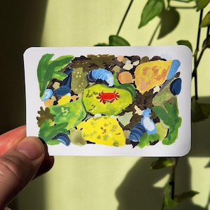 Puede incluir: Una impresión artística rectangular con una pintura abstracta en varios colores. La obra de arte incluye tonos de verde, amarillo, azul y marrón, con un elemento rojo central. La impresión se sostiene sobre un fondo verde claro con sombras de plantas.