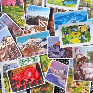 May include: A collection of rectangular art prints featuring various landscape paintings. The prints showcase scenes of mountains, forests, and a red cat. The artwork is rendered in a colorful, painterly style, with a focus on natural elements.