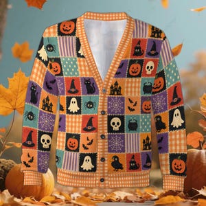 May include: A long-sleeve button-down cardigan featuring a patchwork pattern of Halloween motifs including pumpkins, skulls, ghosts, black cats, spiders, spiderwebs, bats, and haunted houses in orange, purple, black, and white colors.