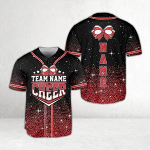 Könnte beinhalten: Schwarzes Baseball-Trikot mit roten Akzenten und Glitzereffekt. Auf der Vorderseite steht der Text "TEAM NAME CHEER" und ein Schleifendesign. Die Rückseite hat ein Schleifendesign und das Wort "NAME" vertikal.