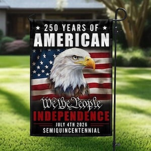May include: A black garden flag with the text "250 YEARS OF AMERICAN" and "We the People INDEPENDENCE JULY 4TH 2026 SEMIQUINCENTENNIAL". The flag features an American flag design and a bald eagle.