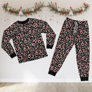 May include: Black pajama set with a festive pattern. The long-sleeved top and pants feature a repeating design of candy canes, the number 67, and snowflakes. The cuffs and neckline are solid black.