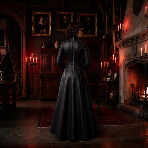 May include: A floor-length black leather coat featuring a high collar, long sleeves, and a full-length vertical zipper down the back. The coat is accented with thin red piping along the seams and a fitted waistline, creating a structured silhouette.