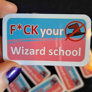 Pode incluir: Um autocolante retangular com cantos arredondados. A metade superior é azul claro com as palavras "F*CK your" em vermelho e branco. A metade inferior é rosa com as palavras "Wizard school" em branco. Um chapéu de bruxo castanho está riscado.