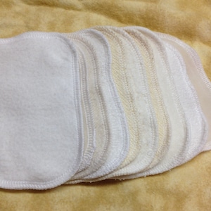 May include: A stack of white and off-white reusable makeup remover pads with a stitched edge.