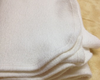 May include: A stack of white fleece fabric, folded neatly. The fabric is soft and plush, with a subtle texture.