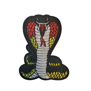 Pode incluir: Patch bordado com um desenho de cobra. A cabeça da cobra está levantada, mostrando uma língua vermelha e um padrão detalhado de escamas vermelhas, amarelas e verdes. O patch tem uma borda preta e um fundo branco.