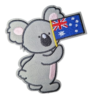 May include: Embroidered patch of a grey koala holding a small Australian flag. The koala has pink inner ears and a black nose. The flag is blue with white stars and the Union Jack. The patch has a grey border.