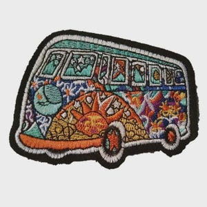 Op de afbeelding: Geborduurde patch met een kleurrijk, gedetailleerd ontwerp van een vintage busje. Het busje is versierd met een zon, maan en diverse geometrische patronen in tinten oranje, blauw, groen en paars. De patch heeft een zwarte rand.
