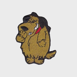 May include: Embroidered patch featuring a cartoon dog with a black hat and a red collar. The dog is smiling and appears to be laughing, with one paw raised. The patch has a textured, stitched appearance and is in shades of brown and black.