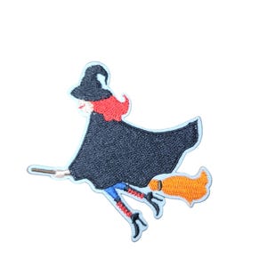 May include: Embroidered patch depicting a witch in a black hat and cloak, riding a broom. The witch has red hair and is wearing blue and red striped stockings. The broom is orange, with a white border.