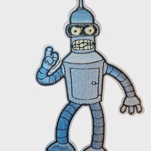 Può includere: Toppa ricamata raffigurante il personaggio Bender della serie animata Futurama. La toppa mostra Bender in varie tonalità di blu con contorni neri, dando un effetto 3D. Bender fa il pollice in su con un ampio sorriso.