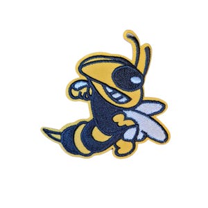 Op de afbeelding: Geborduurde patch met een cartoon-achtige gele en zwarte bij met een lachend gezicht en witte vleugels. De patch heeft een gele rand en is ontworpen om op stof te strijken of te naaien.