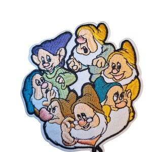 May include: Embroidered patch depicting the seven dwarfs from Snow White. The patch shows the dwarfs in various poses, with details like their hats, beards, and expressions. The patch has a white border and is designed for application on clothing or accessories.