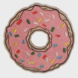 May include: Embroidered patch in the shape of a pink donut with colorful sprinkles. The patch has a brown border and a hole in the center. This patch is suitable for decorating clothing, bags, or other fabric items.