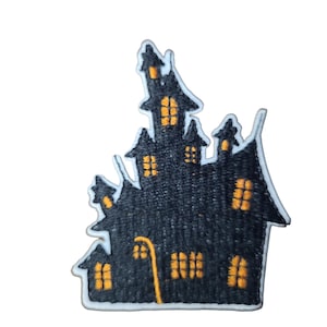 Może przedstawiać: Czarna, haftowana naszywka przedstawiająca nawiedzony dom z pomarańczowymi oknami i latarnią uliczną. Naszywka ma białą obwódkę i jest idealna do rękodzieła i odzieży na Halloween.